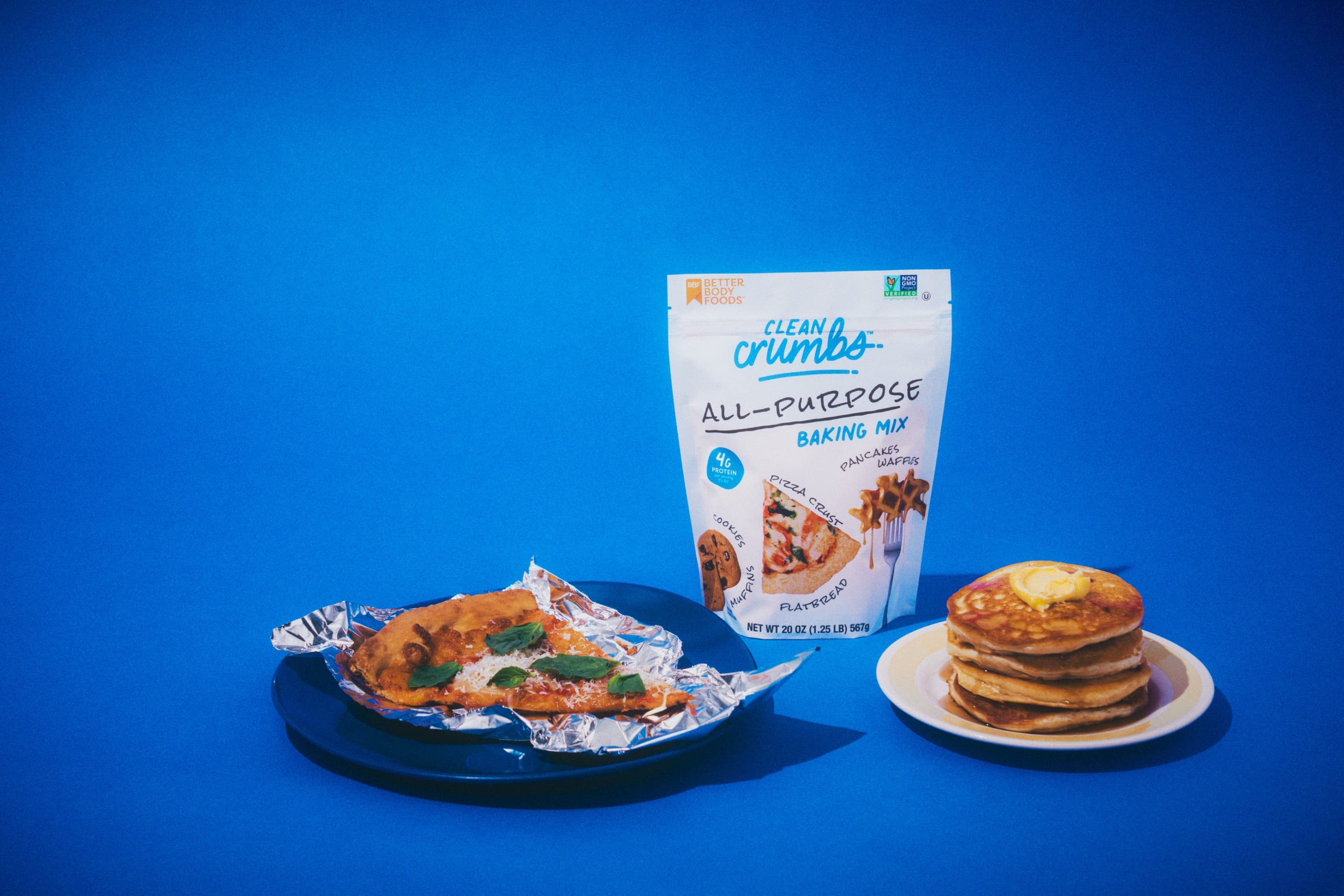 Clean Crumbs all-purpose baking mix bag with a pizza crust and a stack of pancakes